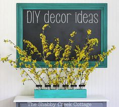 yellow flowers are in vases sitting on a blue dresser next to a chalkboard