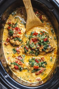 a crock pot filled with chicken, spinach and tomato sauce in the slow cooker