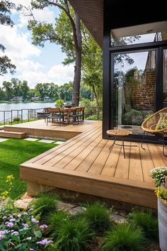 an outdoor deck with chairs and tables next to the water