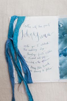 the wedding stationery is laid out with blue and white ink