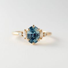 a blue diamond ring with three diamonds on the band and an oval cut stone in the center