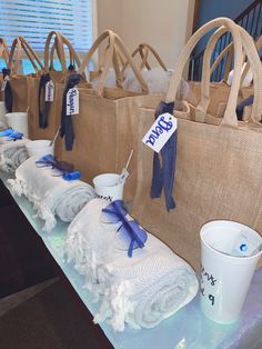 several bags are lined up on a table with towels and cups in front of them