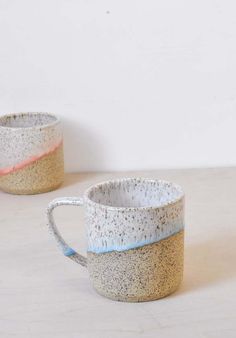 two coffee mugs sitting next to each other on top of a white countertop