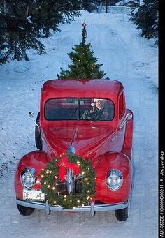 an old red car with a christmas tree on the back