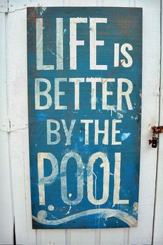 a sign that says life is better by the pool on a white door with blue paint