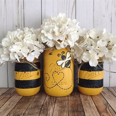 three jars with flowers in them sitting on a table