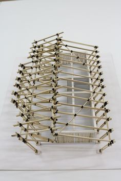 a sculpture made out of sticks and nails on top of a white surface with an open window in the middle