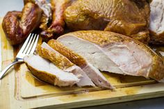 a wooden cutting board topped with sliced turkey