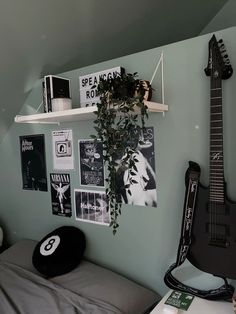 a guitar is hanging on the wall next to a bed with a plant in it