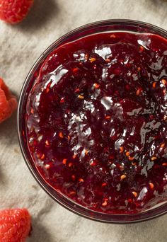 raspberry sauce in a glass bowl surrounded by fresh raspberries