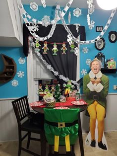 a table with decorations on it in front of a blue wall and snowflakes hanging from the ceiling