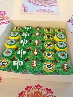 cupcakes in a box with green and yellow frosting are arranged on top of each other