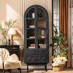 a living room filled with furniture and a tall black china cabinet next to a window