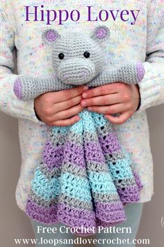 a woman holding a crocheted hippo lovey in her hands