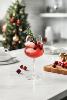 a wine glass filled with red liquid and topped with a sprig of rosemary