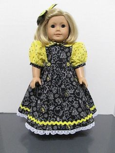 a doll with blonde hair wearing a black dress and yellow polka dot shirt, standing on a table