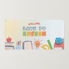 a welcome back to school sign hanging on the side of a white wall with an apple, books and pencils