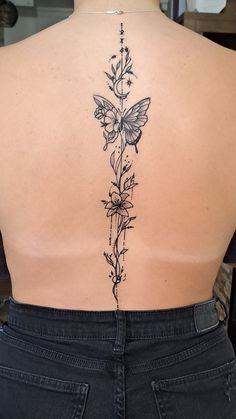 the back of a woman's body with flowers and butterfly tattoos on her lower back