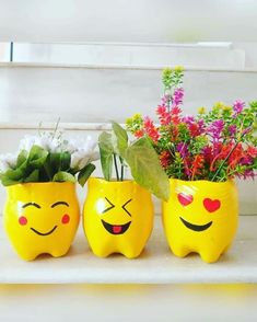 three yellow smiley face planters sitting on top of a white shelf next to flowers