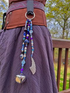 a woman wearing a purple dress with beads and charms on it's waist belt