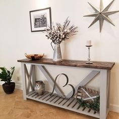 a wooden table topped with a vase filled with flowers and two candles on top of it