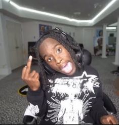 a woman with dreadlocks is making the peace sign in an office building while wearing headphones