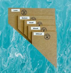 four envelopes with labels on them sitting in front of blue water, one is empty