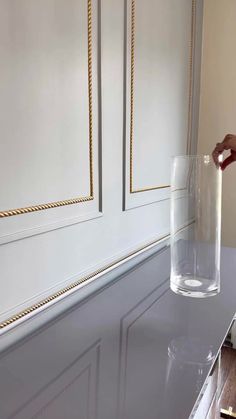 a person pouring water into a glass on top of a table with gold trimmings