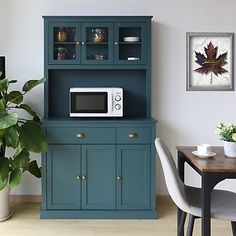 a kitchen area with a microwave, potted plant and dining room table