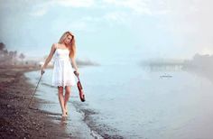 a woman walking on the beach with an umbrella in her hand and holding a stick