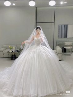 a woman in a white wedding dress standing in front of a mirror wearing a veil