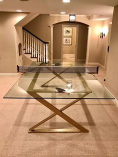 a glass coffee table in the middle of a living room with stairs leading up to it