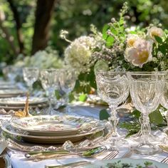 the table is set with plates, silverware and floral centerpieces on it