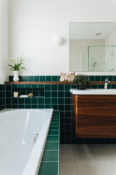 a bath room with a tub a sink and a mirror on the wall in it