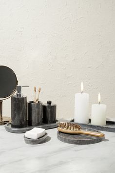 a marble counter top with candles, soap dispenser and brush on it