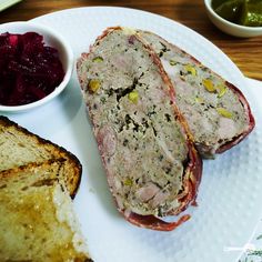 two slices of meat are on a plate with bread and cranberry compote