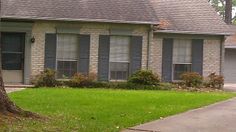 a red fire hydrant sitting in front of a brick house with shutters on the windows