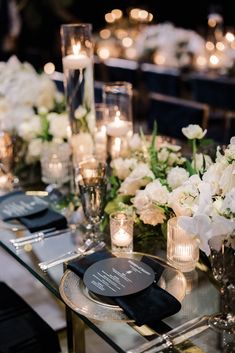 the table is set with candles, flowers and plates for an elegant wedding reception in black and white