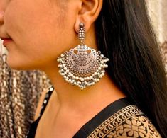 These stunning drop earrings are styling delight lightweight and easy to wear, these earrings will be your go-to accessory. It features intricate motifs that add an ethereal and edgy touch to the look. Style this up with your straight kurtas or pair them up with your indo-western outfits, these will make you look bolder & chic! Silver Temple Jewelry Chandelier Earrings With Latkans, Festive Silver Chandelier Earrings With Tilla, Traditional Silver Chandelier Earrings For Festive Occasions, Silver Chandelier Earrings With Tilla For Gifts, Elegant Silver Danglers For Navratri, Dual-tone Drop Danglers, Traditional Oxidized Chandelier Earrings For Festive Occasions, Dual-tone Earrings For Diwali, Silver Chandbalis For Festive Navratri