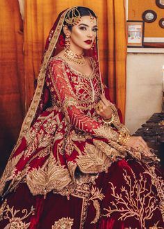 a woman in a red and gold bridal gown sitting on a table with candles