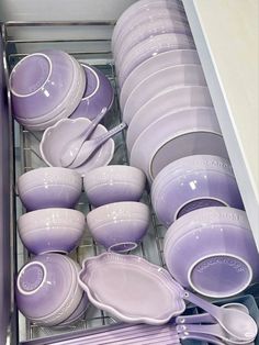 purple dishes are stacked in the dishwasher and organized with white plates, silverware, and pink utensils