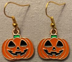 two halloween pumpkins with faces on them are hanging from gold earwires,