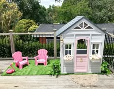 two pink lawn chairs sitting on top of a wooden deck next to a small shed