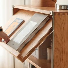 a person opening a book on top of a wooden shelf