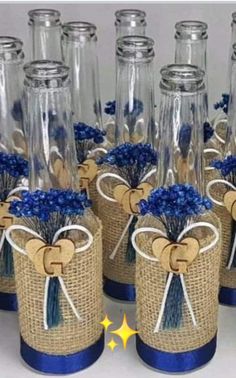 there are many glass vases with blue flowers in them and tied to burlocks