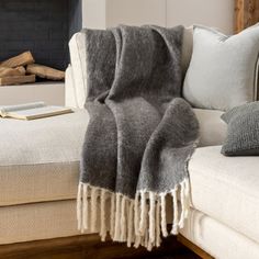 a living room with a couch, chair and fire place covered in grey throw blankets