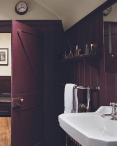 a bathroom with a sink, mirror and wooden shelves on the wall next to it