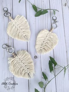 two white sheepskin purses sitting on top of a wooden table next to green leaves