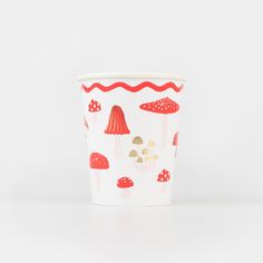 a white cup with red mushrooms on it