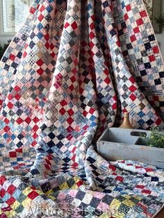 a quilt is hanging from the ceiling in front of a window